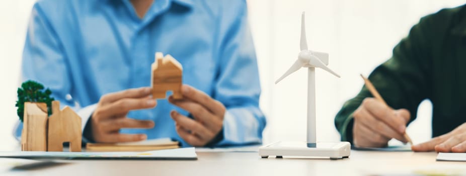 Business people invest in green business plan at meeting room on table with house model and wind mill placed represented eco house and renewable energy. Closeup. Delineation.