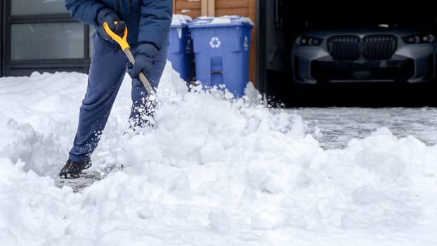 Man shoveling snow off of his driveway after a winter storm in Canada. Man with snow shovel cleans sidewalks in winter. Winter time