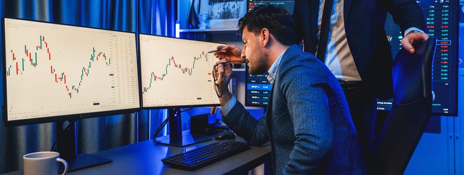 Stock exchange traders looking on high profit chart investment in panorama view, analyzing on monitor at night. Concept of discussing financial technology growth in neon light at workplace. Sellable.