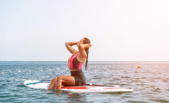 Silhouette of woman standing, surfing on SUP board, confident paddling through water surface. Idyllic sunset or sunrise. Sports active lifestyle at sea or river.