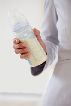 Business, woman and baby bottle with mom in suit, working and balance a career with motherhood. Hand, closeup and mother with milk in container for child, care and management of family with a job.