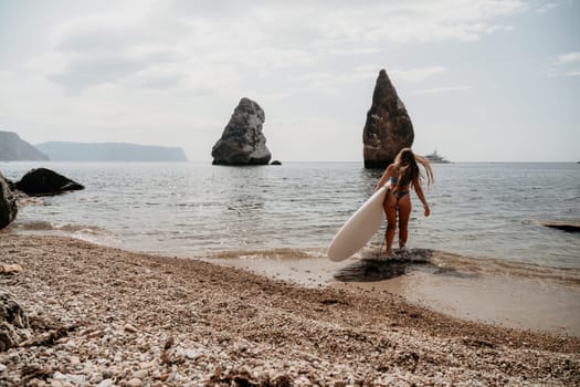 Close up shot of beautiful young caucasian woman with black hair and freckles looking at camera and smiling. Cute woman portrait in a pink bikini posing on a volcanic rock high above the sea