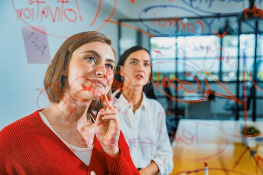 Creative business team brainstorming and sharing marketing idea about start up project by writing down on colorful sticky note at glass board modern meeting room. Working together. Immaculate.