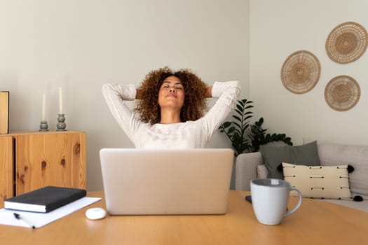 Front view of young multiracial hispanic female entrepreneur relaxing at home office taking a break feeling satisfaction. Lifestyle and business concept.