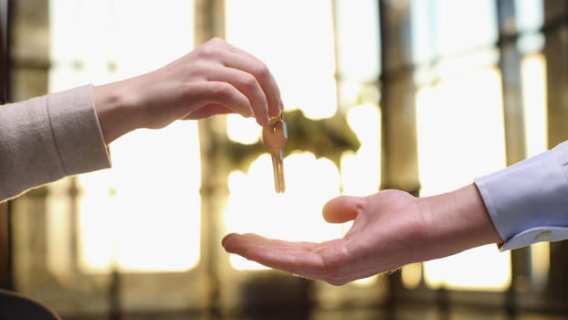 From hand to hand. Close up shot of hand of female seller owner of house apartment office holding keys giving it to young woman buyer renter after conclusion of successful deal and getting downpayment