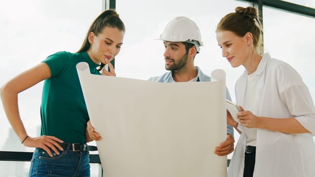 Professional architect engineer team thinking, sharing, brainstorming about design while looking at project plan. Young architect holding plan while young beautiful manager taking a note. Tracery