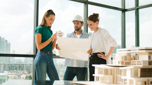 Professional architect engineer team talking, sharing, brainstorming about design while manager hold at project plan. Young architect holding plan while manager listen and point at plan. Tracery