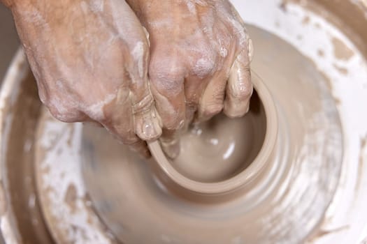 male hands making ceramic cup on pottery wheel, Close-up, top view