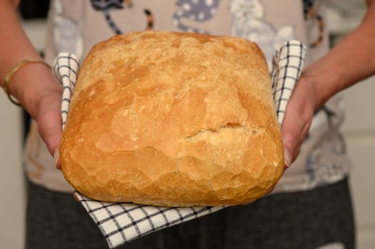 freshly baked bread at home in the hands of a woman in the kitchen 3