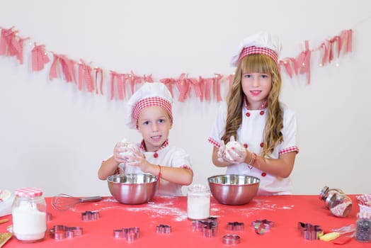 happy smiling children in apron and chef hat cooking cookies with flour, eggs, chocolate and water. Kitchen and family. Happy kids.