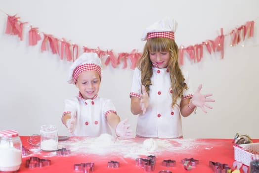 happy smiling children in apron and chef hat cooking cookies with flour, eggs, chocolate and water. Kitchen and family. Happy kids.