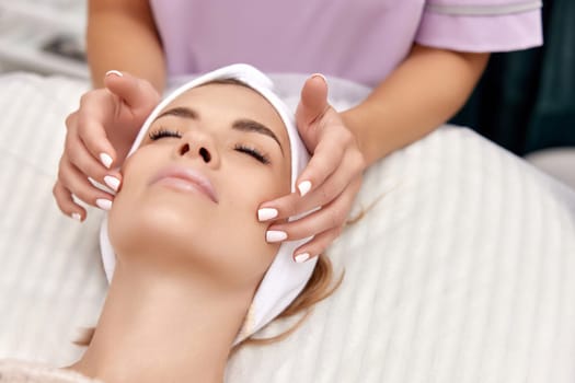 Beautiful woman getting face massage treatment in beauty salon. girl enjoys this procedure.