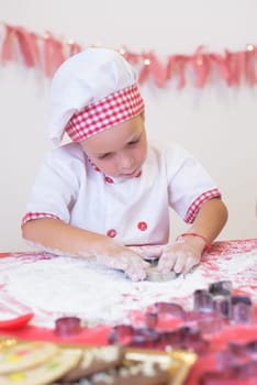 happy smiling child in apron and chef hat cooking cookies with flour, eggs, chocolate and water. Kitchen and family. Happy kids.