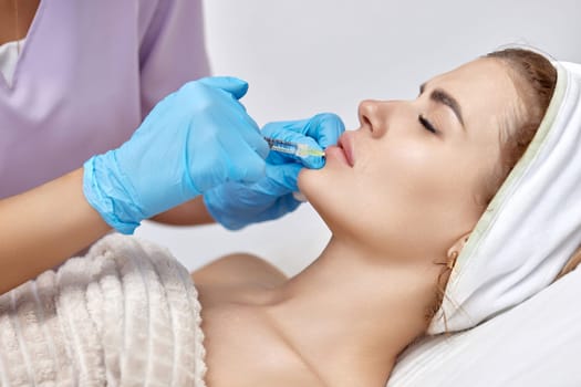 cosmetologist makes injections to enlarge the lips of beautiful woman. Woman in beauty salon. plastic surgery.