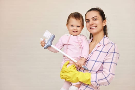 happy mother housewife is holding cute little child girl and doing housework at home , Happy family, copy space
