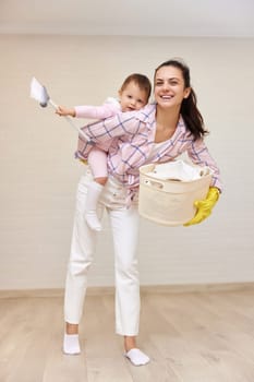 happy mother housewife is holding cute baby girl and basket with laundry , Happy family