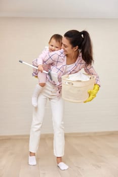 happy mother housewife is holding cute baby girl and basket with laundry , Happy family