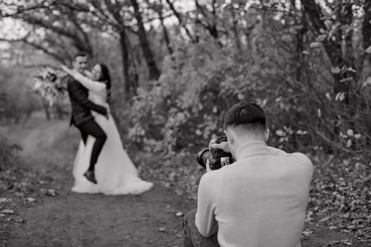 Professional wedding photographer taking pictures of the bride and groom in nature in autumn