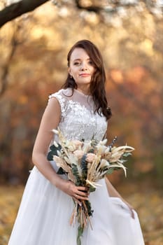 beautiful happy bride holding wedding autumn bouquet in nature