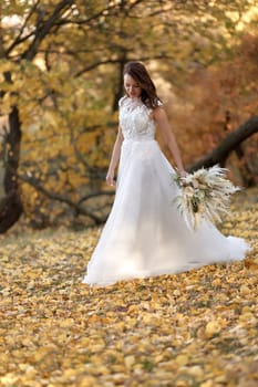 beautiful happy bride holding wedding autumn bouquet in nature