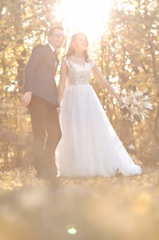 beautiful bride in white wedding dress and groom standing outdoor on natural background in sunny day