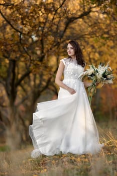 beautiful happy bride holding wedding autumn bouquet in nature