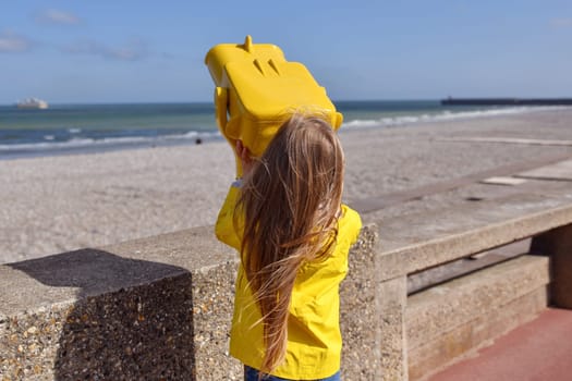 Girl looking at the ocean through a binoscope