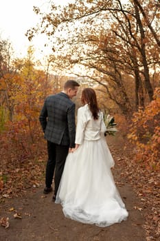 bride in white wedding dress and groom walking outdoor on natural background