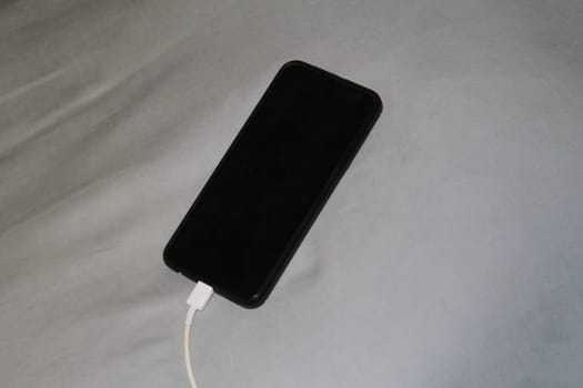 The smartphone is charged from a the charger in bed