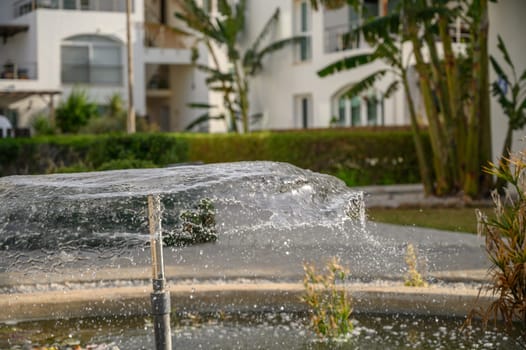 a fountain sprays water against the backdrop of a residential complex near the sea 5
