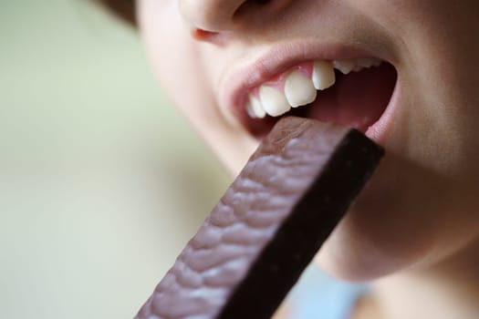 Crop unrecognizable teenage girl with mouth open about to eat healthy protein bar at home