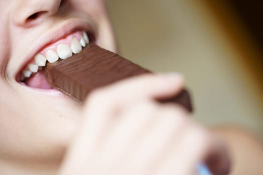 From below closeup of happy crop anonymous teenage girl biting nutritious protein bar at home