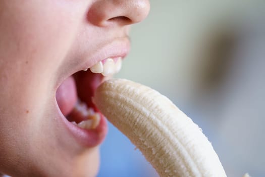 Closeup of crop unrecognizable young girl about to eat delicious peeled banana at home