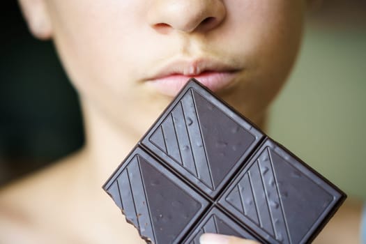 Closeup of crop unrecognizable teenage girl holding chocolate bar at home