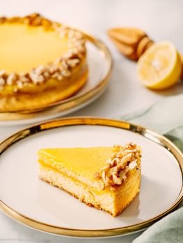 Piece of delicious vegan lemon tart or lemon cake, modernly decorated with walnuts on aesthetic plate. Aesthetic of traditional classic french lemon pie with lemon curd recipe. Vertical, copy space