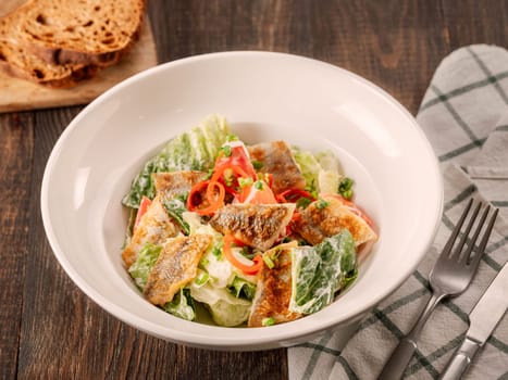Delicious salad with fried baked smelt fish. Fried fish salad with fresh green lettuce, tomatoes, bell pepper. Ketogenic, keto or paleo diet lunch bowl. Ideas and recipe for fish lunch dishes menu
