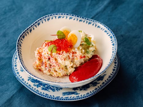 Mayonnaise salad with crab meat, decorated with beetroot mousse in restaurant-style plating. Imitation crab salad with crab sticks or crab meat and eggs in bowl on blue background