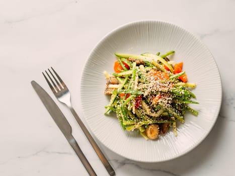 Delicious pork meat salad with cucumber in asian style with amaranth popcorn or popped amaranth (replaceable sesame) on white marble background. Topview, copyspace. Idea salad recipe healthy food menu