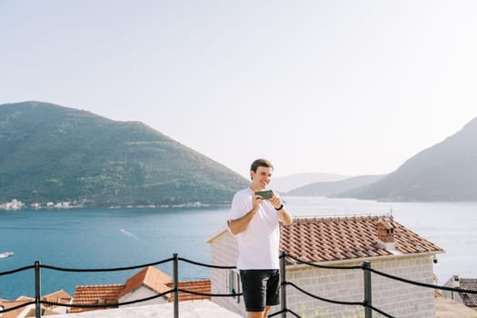 Man shoots with a smartphone while standing on a platform above the sea. High quality photo