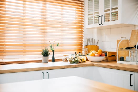 In this Scandinavian interior, a modern kitchen with grey design tiles and wooden furniture stands out. A big window and a plant add to the luxury of this cozy, clean home in white.