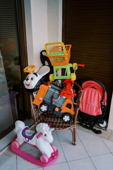Colorful children toys lie on a chair on the balcony against the wall. High quality photo