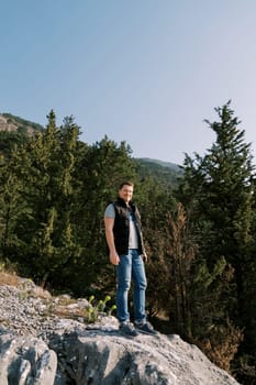 Smiling man stands on a stone hill in the mountains. High quality photo