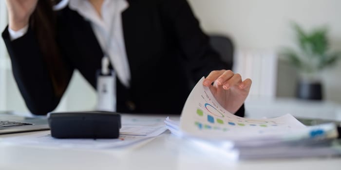 Business accounting woman counting on calculator working on financial document in hands closeup. Bookkeeping concept.