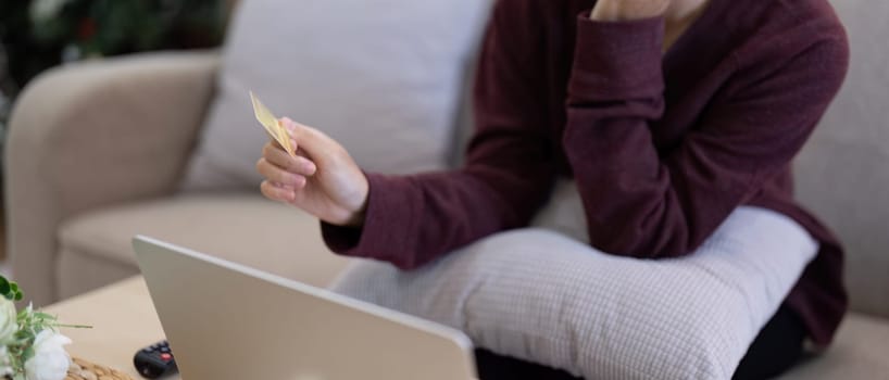 Young Asian woman hands holding credit card and using laptop for internet purchase. Online shopping, Online payment at home.