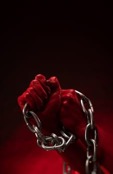 bloodied hands clenched into fists in the shackles of a metal chain symbolize slavery, protest and struggle for freedom