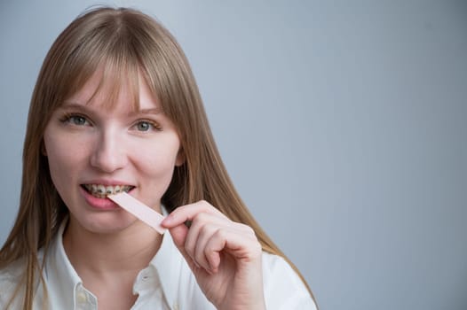 Young woman with metal braces on her teeth is chewing gum. Copy space