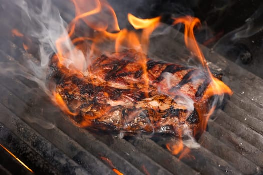 Close up searing and smoking ribeye beef steaks on open fire outdoor grill with cast iron metal grate, high angle view