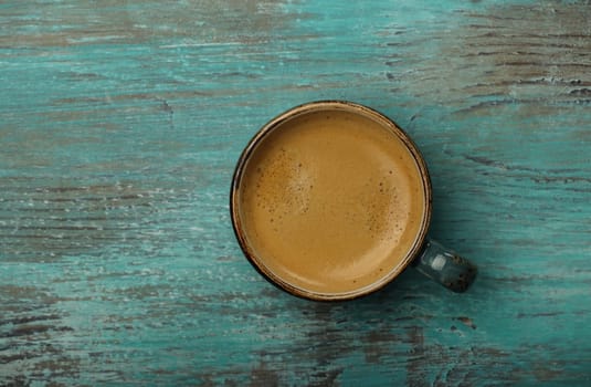 Close up one full espresso coffee cup on grunge teal blue table surface, copy space, high angle view, directly above