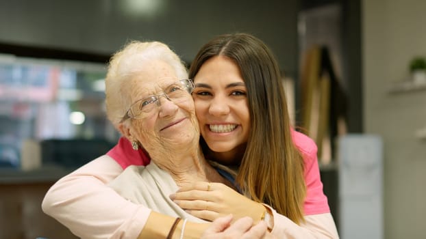 Photo of grandmother and granddaughter smiling at camera very happy