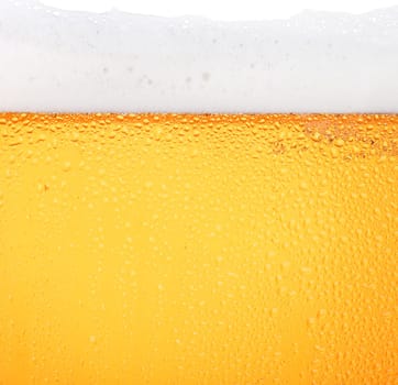 Close up background texture of pouring lager beer with bubbles and froth in frosty glass with drops, low angle side view